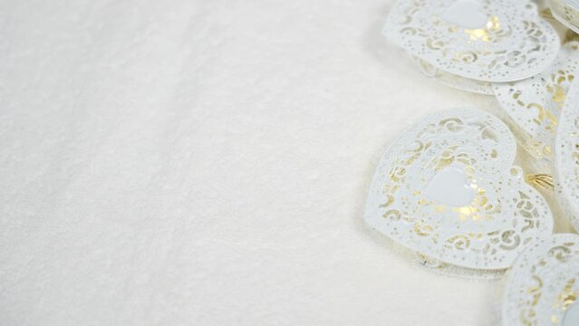 4k stock video footage of close up top view of beautiful manicured female hand touching soft fluffy texture of white towel. Shiny holiday hearts decor laying on white cotton background