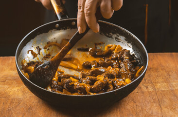 The cook prepares meat with vegetables and onion in a bowl . Oriental cuisine