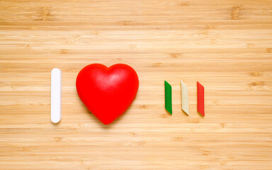 I love Italy. Red heart and pasta in the colors of the flag of Italy on a wooden background.