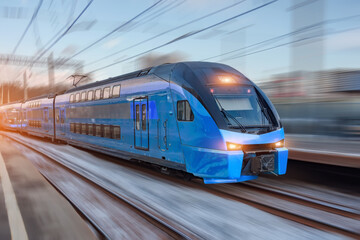 Electric passenger train drives at high speed among urban passenger station.