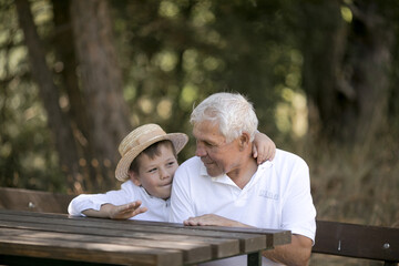 Happy senior man Grandfather with cute little boy grandson playing in forest