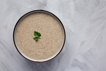 Homemade Cream of Mushroom Soup in a Bowl on a gray background, top view. Flat lay, overhead, from above.