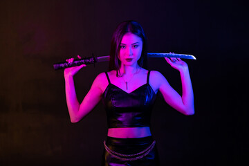 Beautiful asian girl with katana sword in neon lights.