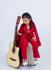 Adorable 6 years old asian girl in red dress, holding a fashionable handbag in a studio isolated on white background. 