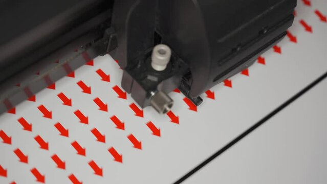 Cutting plotter machine making small round red arrows stickers, closeup detail