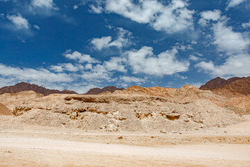 Rocky desert hills under blue sky with white clouds on clear day