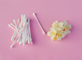 White buds near white jasmine flowers on light pink, close up. Skincare product for everyday beauty...