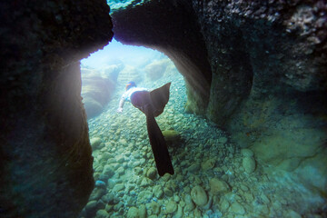 Free diving people apnea underwater go through a cave with nice blue ocean scenery is extreme relax sport on holiday.