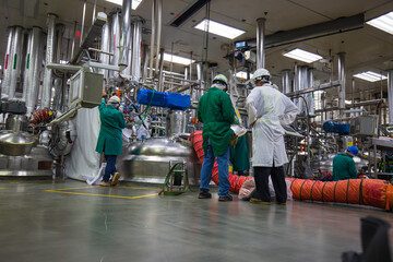 Male worker do  inspection  and record process pressure meter in equipment tank facility at the vertical stainless steel