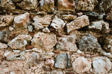 Brick wall of old faded cobblestones as background. Grunge texture. Loft style.