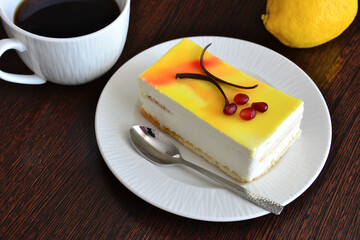 healthy lemon cheesecake on white saucer with teaspoon and cup of coffee, macro