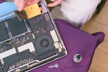 Man removing the battery of a laptop from adhesive stripes via a plastic card. Lithium Ion. Laptop...