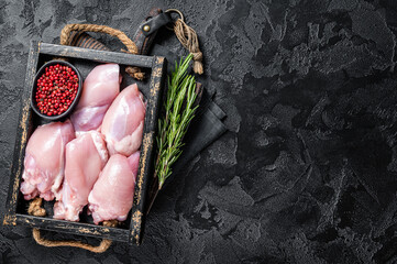 Raw Boneless and skinless Chicken leg thigh fillet with herbs. Black background. Top view. Copy space
