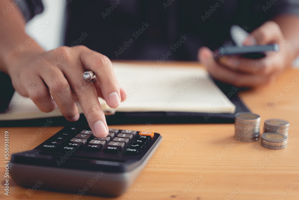 Poster investors are using a calculator to calculate investment costs while holding a smartphone.