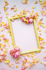 Rose petals, rose buds and empty wooden frame on light pink background. Flat lay, copy space. Mother's Day, St. Valentine's Day, March 8 concept. Top view, flat lay. Card design template.