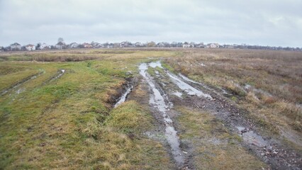 Fototapeta na wymiar A dirt road with puddles across a field