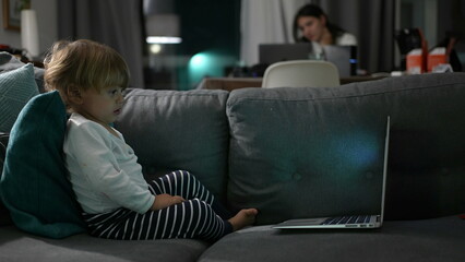 Toddler boy watching cartoon at night sitting in sofa