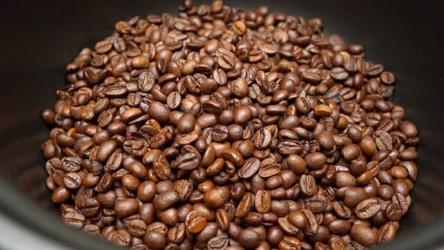 Kaffeebohnen drehen sich in Zeitlupe in einen Behälter 4