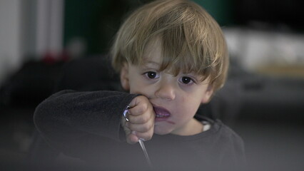 Toddler boy refusing food while watching cartoon in front of screen