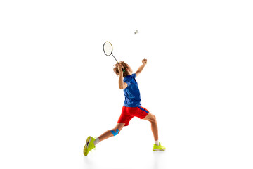 Fototapeta na wymiar Portrait of teen boy in uniform in motion, playing badminton, serving shuttlecock with racket isolated over white background