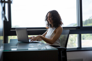woman working on laptop, woman sitting in front of her computer, woman working from home office, student and her computer
