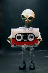 alien with a microcassette in his arms
