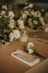 White flowers on gray tablecloth with candles, cutlery and menu. Wedding decoration.