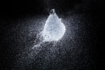 Water balloon explosion splashing in form shape, is power refreshing freshness concept. Waters Balloon explode and droplet spill all around with freeze high speed shot in black background studio