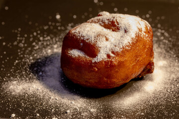 Oliebol in black background served with white icing sugar powder, Traditional Dutch food or sweet known as doughnuts or dutchies, Oliebollen are traditionally eaten on New Year's Eve, Netherlands.