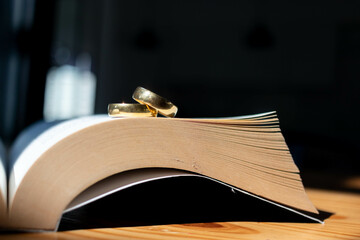 Two wedding rings are placed on the open Bible placed on the table as wedding rings prepared for lovers to wear and read Bible passages as a promise to each other. Copy Space for text