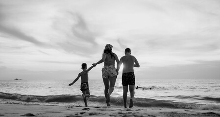 Fototapeta na wymiar People running on the beach. Black and white toned image 