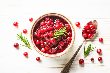 Cranberry sauce in a bowl at white wooden table. Top view with space for text.