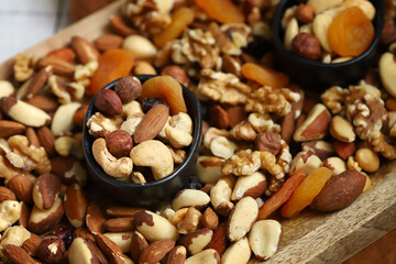 Mix of nuts and dried fruits on a wooden board and in a bowl. Healthy sweets.