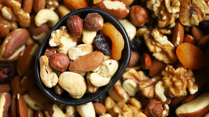 Mix of nuts and dried fruits on a wooden board and in a bowl. Healthy sweets.