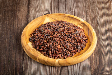 Cocoa nibs on wooden plate.