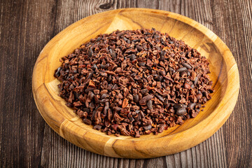 Cocoa nibs on wooden plate.