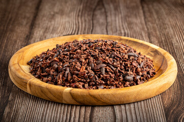 Cocoa nibs on wooden plate.