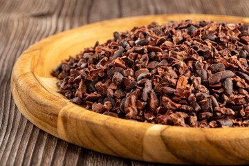 Cocoa nibs on wooden plate.