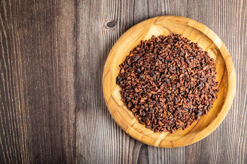 Cocoa nibs on wooden plate.