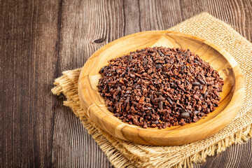 Cocoa nibs on wooden plate.