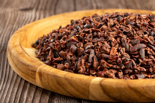 Cocoa nibs on wooden plate.
