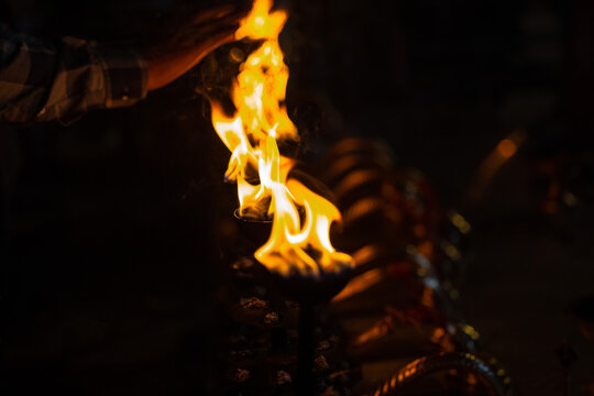Fire flame at night with dark background during the ganga aarti rituals at river bank at Rishikesh, Uttarakhand, India.