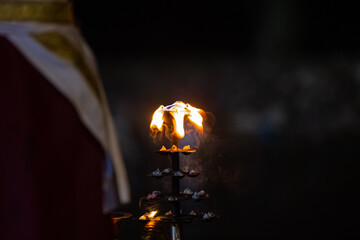 Fire flame at night with dark background during the ganga aarti rituals at river bank at Rishikesh,...