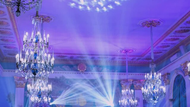 Powerful moving light beams on the ceiling structure in the interior of a public event, fashion show, concert or wedding reception