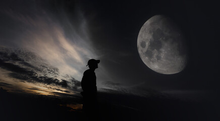 Man standing against moon in the background at night.
