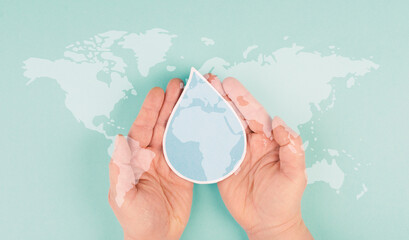Holding a water drop in the hands, silhouette of world map, environment issue, scarcity of...