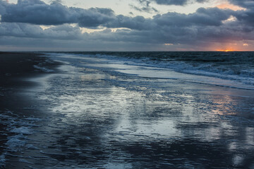 on the sandy Northsea beach sparkles the sunlight in the waves of the sea water