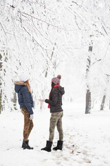 Fototapeta na wymiar Female couple having fun in park while snowing