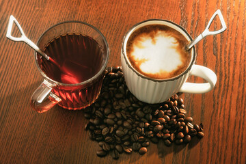 Hot coffee with coffee beans and hot tea on wooden background.
