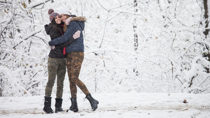 Obraz na płótnie Canvas Female couple having fun in park while snowing